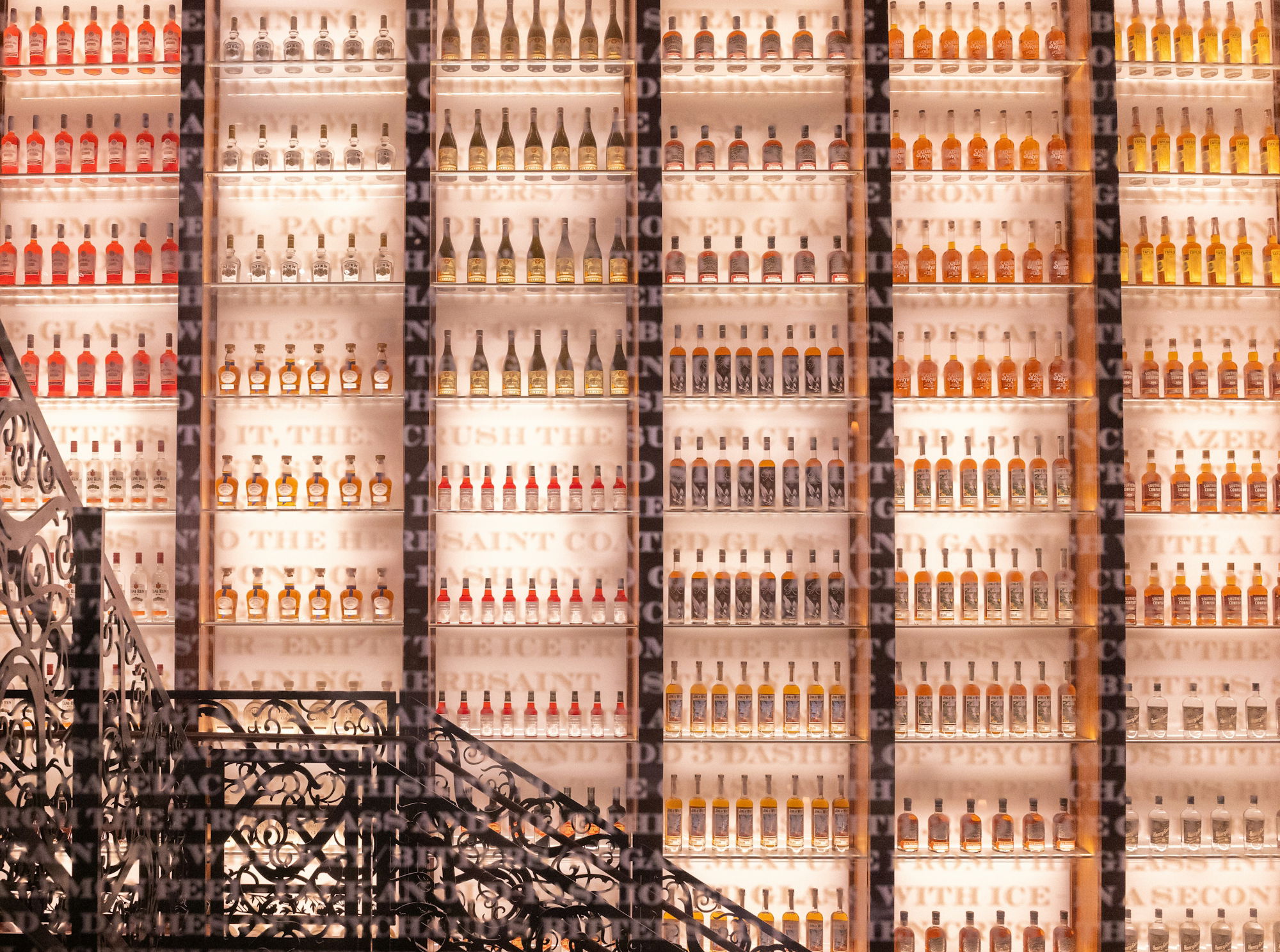 Bottles of alcohol line a brightly lit wall.